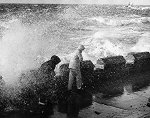 Two people in rain coats are soaked as a wave crashes over the sea front in Ayr Two people in rain coats are soaked as a wave crashes over the sea front in Ayr