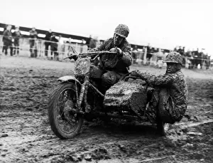Plastered in mud, two competitors race around the tarck in a side car event at Plastered in mud, two competitors race around the tarck in a side car event at