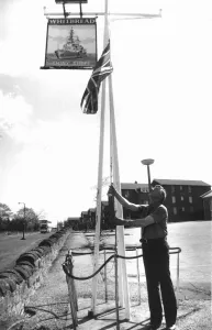Publican Fred Howe lowers the Union Jack outside his hostel Publican Fred Howe lowers the Union Jack outside his hostel