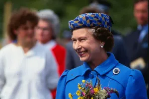 Queen Elizabeth II August 1986 holding flowers wearing a blue coat yellow blue hat on a Queen Elizabeth II August 1986 holding flowers wearing a blue coat yellow blue hat on a