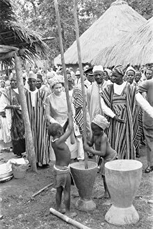 Kenema Collection: Queen Elizabeth watches two children grinding corn during a visit to Hangha in Kenema