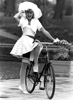 Rubbery Model Jane Sturdy. Wears white outfit, stockings and frilly hat on bicycle Rubbery Model Jane Sturdy. Wears white outfit, stockings and frilly hat on bicycle