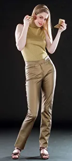 Ruth Kemmer model wearing gold trousers and top applying blusher to her face with a brush Ruth Kemmer model wearing gold trousers and top applying blusher to her face with a brush