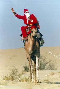 Santa Claus waves from atop his camel in the desert on his way to delivering a message to Santa Claus waves from atop his camel in the desert on his way to delivering a message to