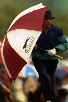Seve Ballesteros holding a golf umbrella at his side whilst walking to the next hole Seve Ballesteros holding a golf umbrella at his side whilst walking to the next hole