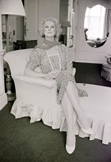 Sex change model April Ashley sitting on a recliner wearing a print dress hands clasped Sex change model April Ashley sitting on a recliner wearing a print dress hands clasped