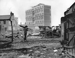 A small boy rummages among the tangled wrecks of old cars on waste ground in A small boy rummages among the tangled wrecks of old cars on waste ground in