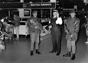 Soldiers with machine guns tand alongside an armed police officer as security is Soldiers with machine guns tand alongside an armed police officer as security is