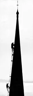 Spotlighted against the wintry city skyline are members of a team of steeplejacks who are Spotlighted against the wintry city skyline are members of a team of steeplejacks who are