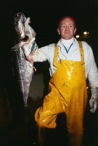 Stanley Robinson fisherman wearing yellow overalls holding large fish April 1989 dock Stanley Robinson fisherman wearing yellow overalls holding large fish April 1989 dock