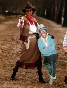 Sue Lawley TV Presenter dressed as a cowgirl with Hat and Gun holding a cardboard cutout Sue Lawley TV Presenter dressed as a cowgirl with Hat and Gun holding a cardboard cutout