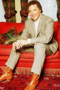 Tom Jones singer sitting on red sette pale suit polo neck jumper glass boots tartan Tom Jones singer sitting on red sette pale suit polo neck jumper glass boots tartan