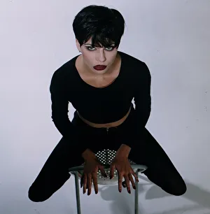 Vamp model sitting on a chair black hair cropped top and leggings red nails lips gothic Vamp model sitting on a chair black hair cropped top and leggings red nails lips gothic