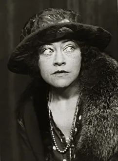 A woman wearing 1920s style clothing including coat, big hat and necklace A woman wearing 1920s style clothing including coat, big hat and necklace