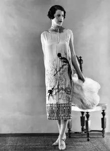 Woman wearing long sleeveless dress with black parrot design at hem Woman wearing long sleeveless dress with black parrot design at hem