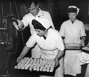 Women baking Swiss Rolls and sultana puddings, put their desserts into the oven during Women baking Swiss Rolls and sultana puddings, put their desserts into the oven during