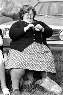 A women with larger figure seen here knitting whilst their children play in a poorer A women with larger figure seen here knitting whilst their children play in a poorer