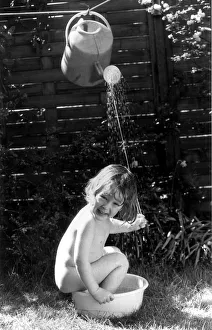 Three year old Tom Bardy is enjoying an improvised shower bath in the back garden of his Three year old Tom Bardy is enjoying an improvised shower bath in the back garden of his