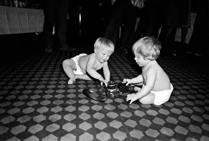 Two young babies seen here examining a camera at a gathering of them parents of a West Two young babies seen here examining a camera at a gathering of them parents of a West