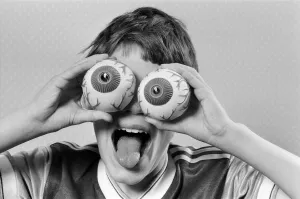A young boy holding fake eye ball toys up to his eyes. 21st October 1986 A young boy holding fake eye ball toys up to his eyes. 21st October 1986