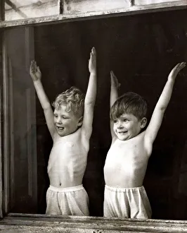 Two young boys doing stretching and breathing exercises in front of an open window at Two young boys doing stretching and breathing exercises in front of an open window at