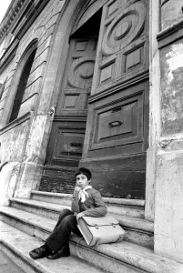 Young child sitting on the steps of an old building in a poor suburb on the outskirts of Young child sitting on the steps of an old building in a poor suburb on the outskirts of