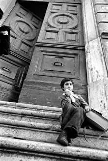 Young child sitting on the steps of an old building in a poor suburb on the outskirts of Young child sitting on the steps of an old building in a poor suburb on the outskirts of