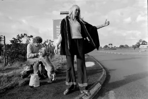A young couple and their dog trying to hitch hike and get a lift on the motorway A young couple and their dog trying to hitch hike and get a lift on the motorway