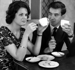 Young couple enjoying cups of tea and biscuits whilst flirting with each other Young couple enjoying cups of tea and biscuits whilst flirting with each other