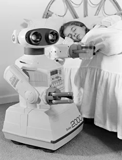 A young girl in bed being woken by an Omnibot 2000 toy robot. 21st October 1986 A young girl in bed being woken by an Omnibot 2000 toy robot. 21st October 1986