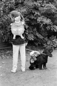 A young girl and a dog wearing a soft toy rucksack. 21st October 1986 A young girl and a dog wearing a soft toy rucksack. 21st October 1986