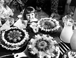A young girl looking at a table with cakes Circa 1970 A young girl looking at a table with cakes Circa 1970