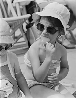 A young girl sitting on the beach, enjoying an ice lolly. 26th June 1979 A young girl sitting on the beach, enjoying an ice lolly. 26th June 1979