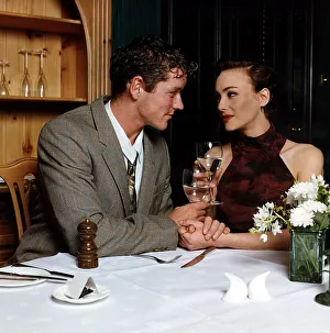 Young man and woman holding hands at dinner table looking into each others eyes Young man and woman holding hands at dinner table looking into each others eyes