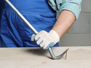 Worker pulling a nail from a plank using a wrecking bar Print