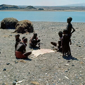 Lake Turkana National Parks Collection: A goat skin stretched in the sun surrounded by women and children of Turkana ethnicity