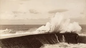 Coastal Scenery Prints: A high wave breaks against a breakwater