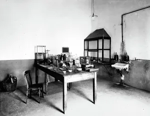 Interior of the Pedani tannery: a table with alembics, testers and various measuring devices are visible; on the walls are a wash basin and a showcase