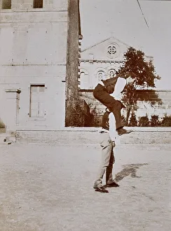 Men In Traditional Clothing Prints: Two men play leapfrog
