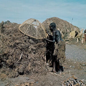 Lake Rudolf Collection: Woman of Turkana ethnicity with the traditional mesh loincloth and deformed legs due to diet