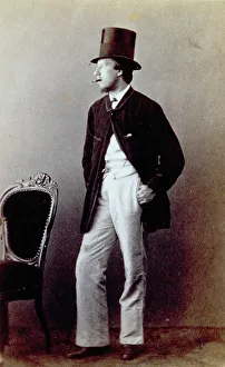 Young man sitting for full-length portrait with cigar