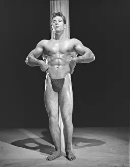 Black And White Muscular Men Prints: Bodybuilder Poses In Front Of Pole c.1954