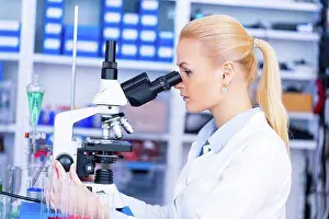 Female Scientist In Lab Prints: Female scientist using microscope in the laboratory