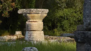 Ancient Olympia Greece Prints: Ancient stone column in shade surrounded by grass and trees