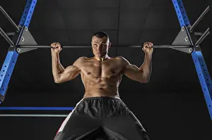 Young Athlete Prints: The athlete pulls himself on the horizontal bar behind his head