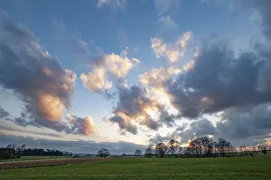 Central European Atmosphere Prints: Atmospheric sunset with cloudy sky and trees and fields in the foreground