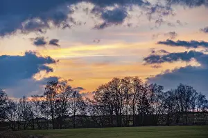 Evening Light In Europe Prints: Atmospheric sunset with cloudy sky and trees and fields in the foreground