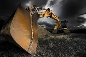 Dark Cloudy Sky Prints: Backhoe bucket excavators with a dramatic sky