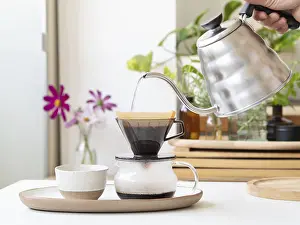 Contemporary Kitchen Setup Prints: Barista preparing filter coffee using a modern kettle and a ceramic dripper