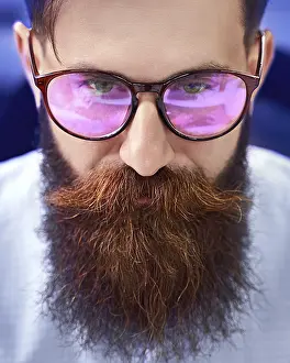 Office Work Desk Scene Prints: Bearded man in glasses with screen reflection working on computer in IT office